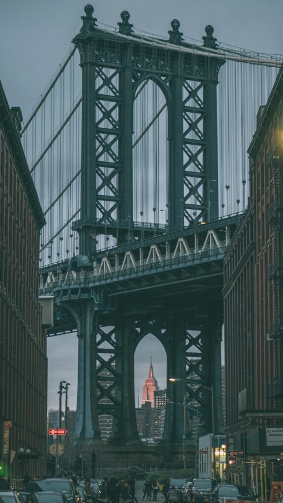 A classic view of the Manhattan Bridge framing the Empire State Building in New York City at dusk.